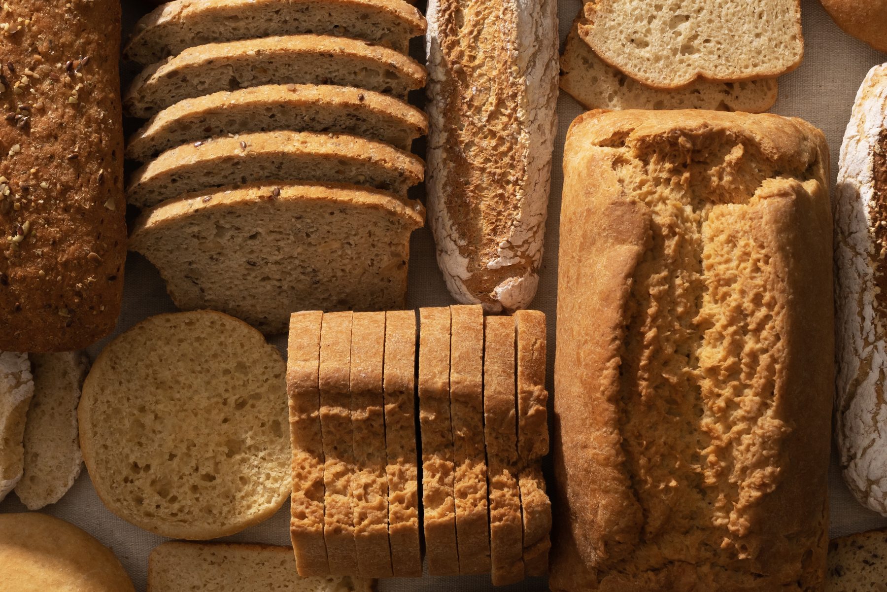 Panes True Food vistos desde arriba: hogazas rebanadas, buns, baguettes y pan de semillas